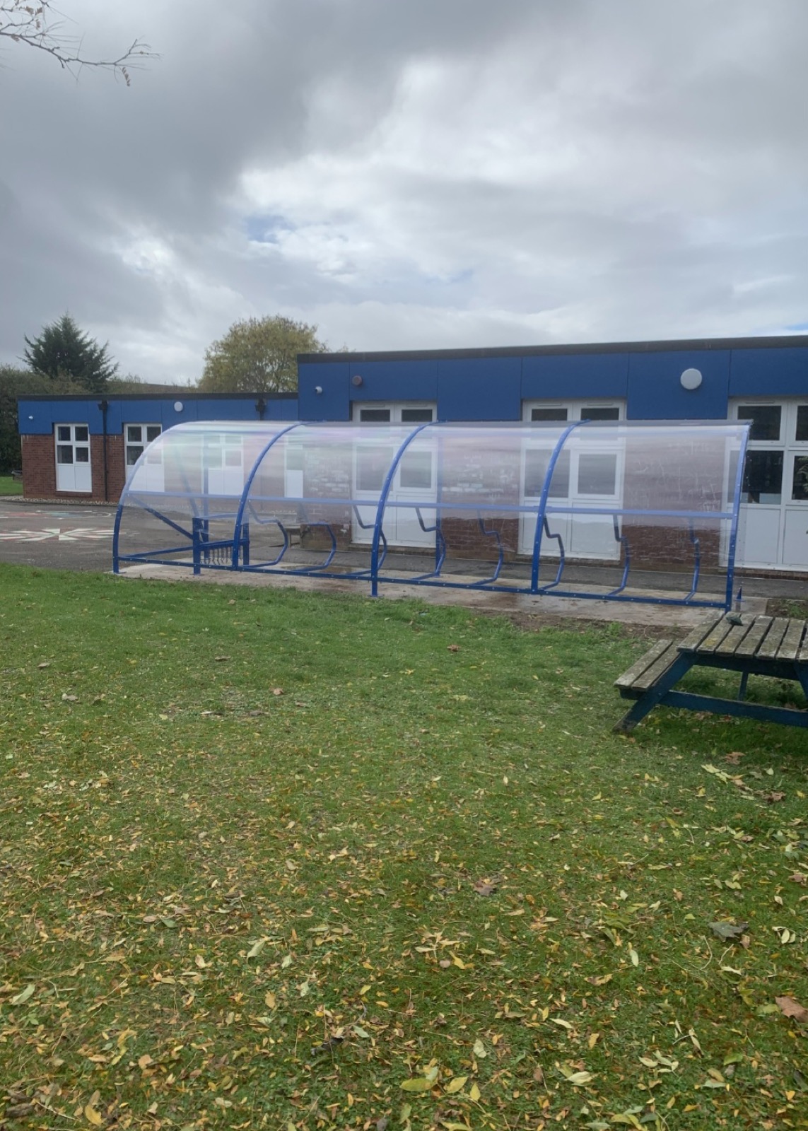 Blue cycle shelter on a grassed area