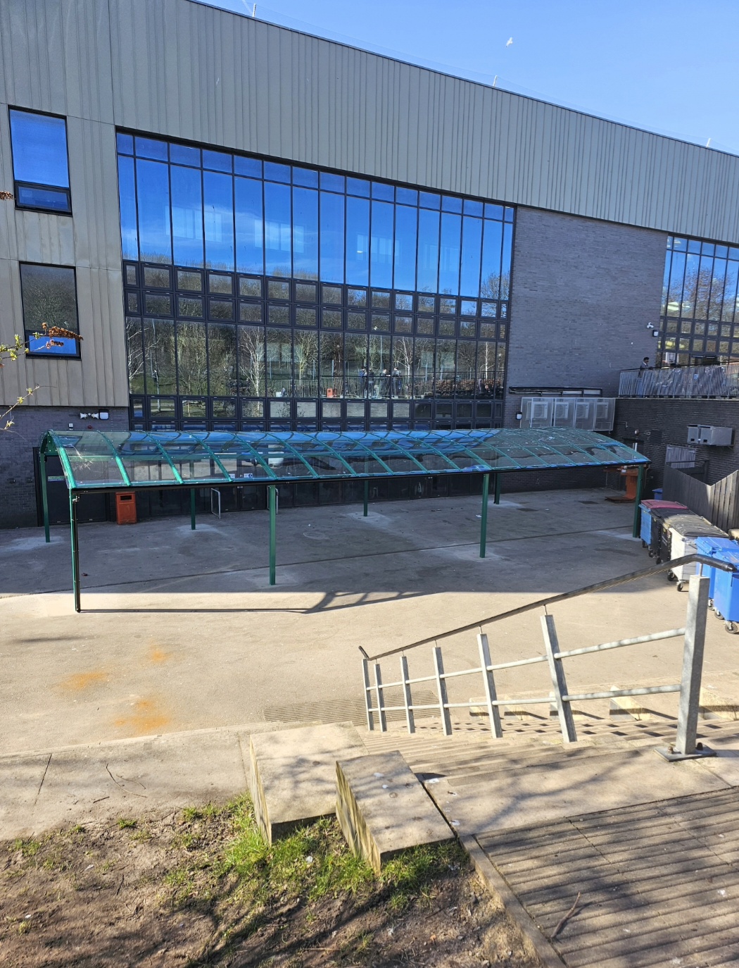 The green dining canopy seen from across the yard, its clear curved roof running the full length