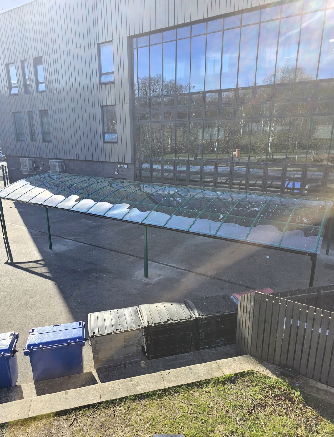 Elevated view of the green dining canopy and its glazed roof beside the building and bin store