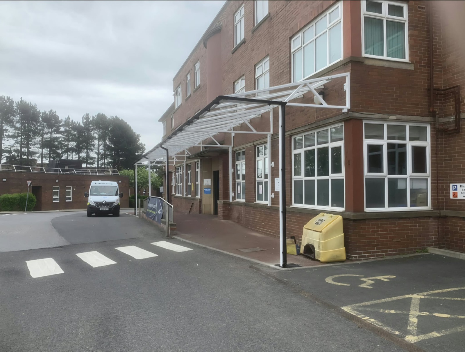 White glazed entrance canopy running along a brick hospital frontage in Liverpool