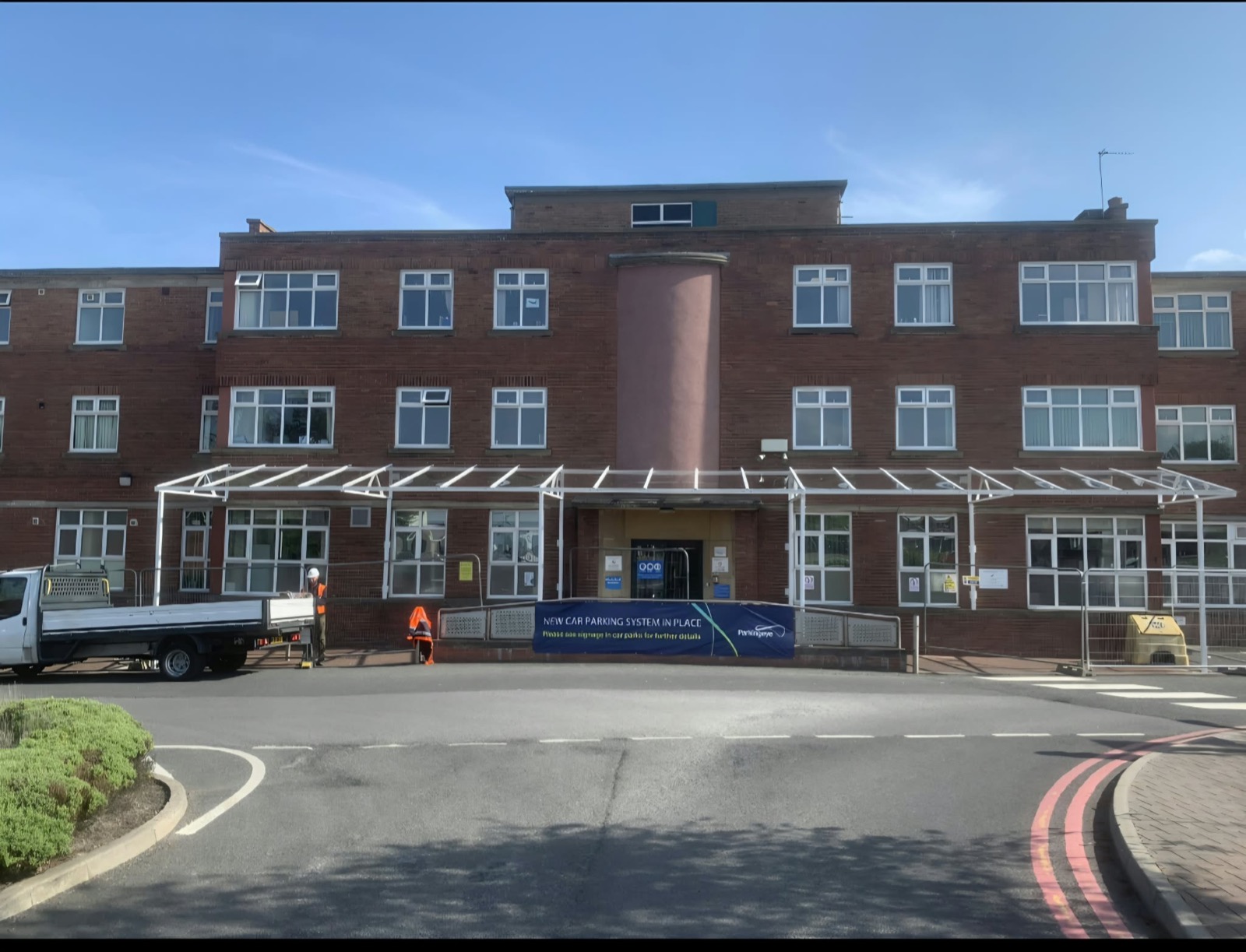 Wide front view of the hospital building with the full-length entrance walkway canopy