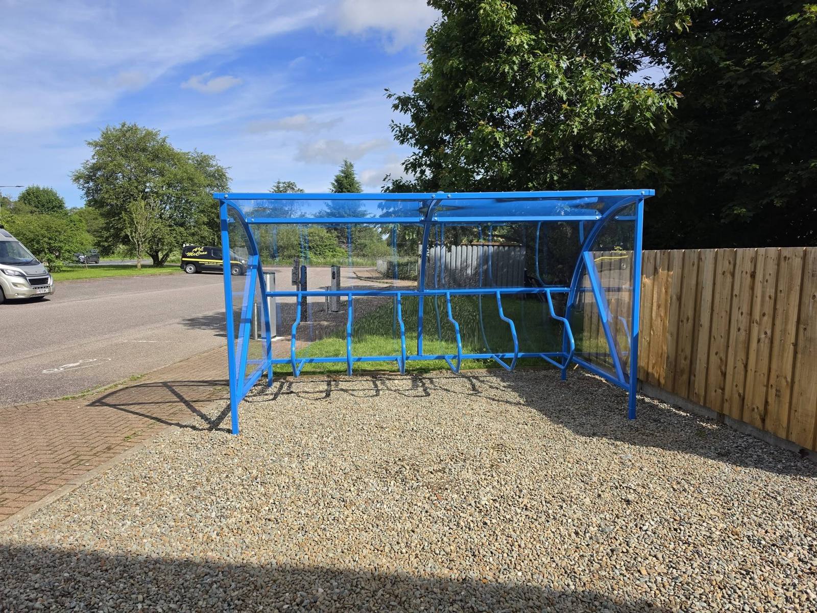 Blue cycle shelter with a clear curved roof installed by Canopies & Shelters Ltd
