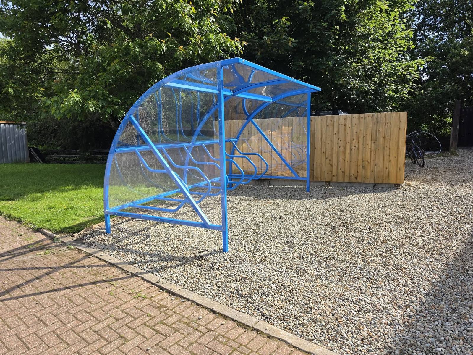 Blue Chelsea cycle shelter with a clear curved roof and cycle rack at MACPool Activity Hub, Lochgilphead