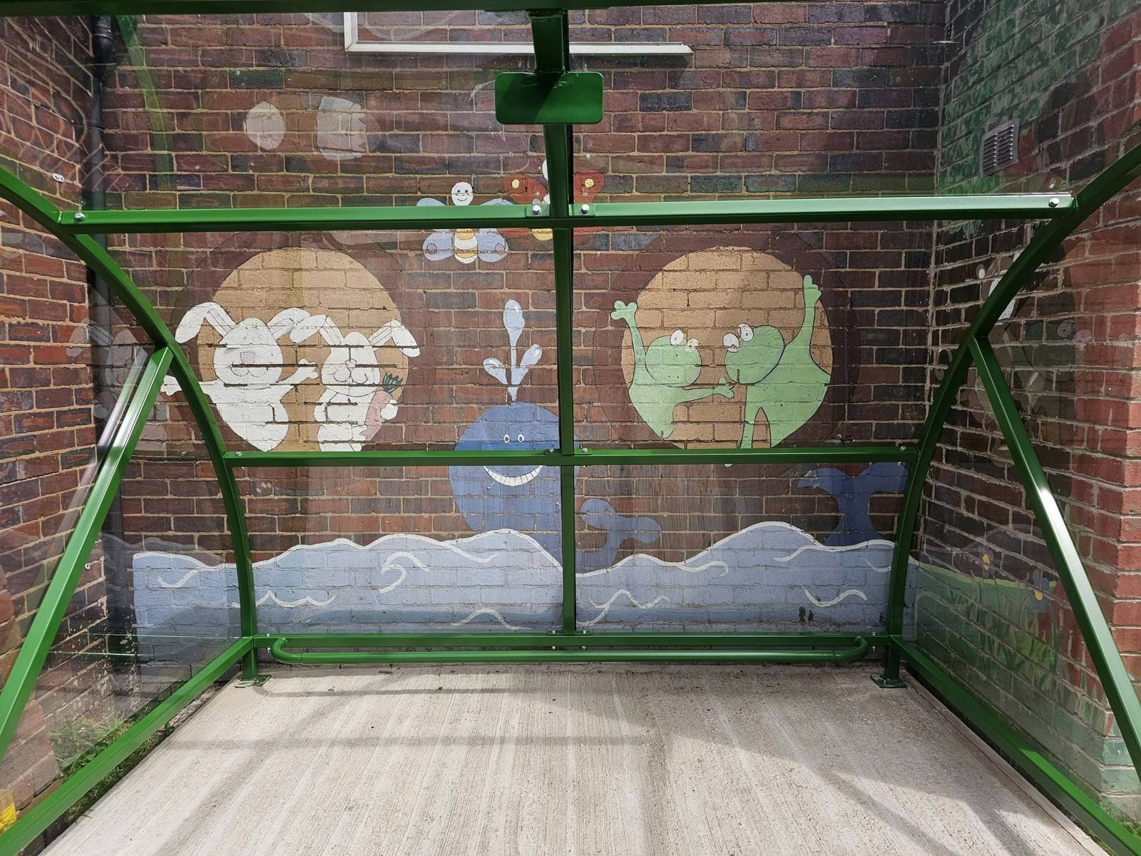 Interior view of the buggy shelter framing a cartoon animal mural on the brick wall