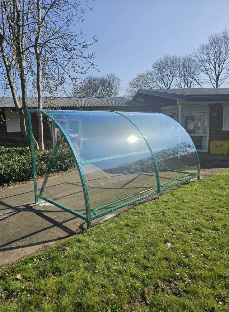 Green curved clear-roofed canopy on a path beside the single-storey building at Rowley and Tipton Family Hubs, Tipton