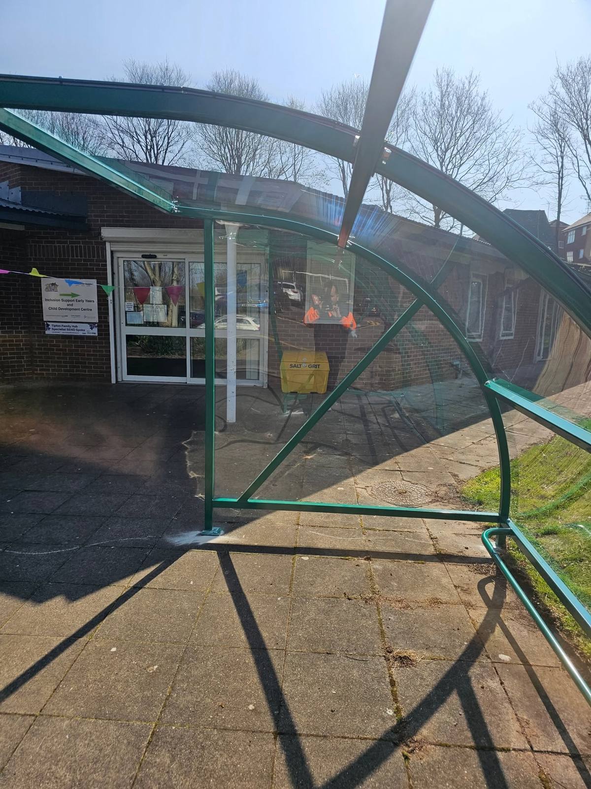 Looking out through the green canopy frame towards the family hub entrance doors and signage