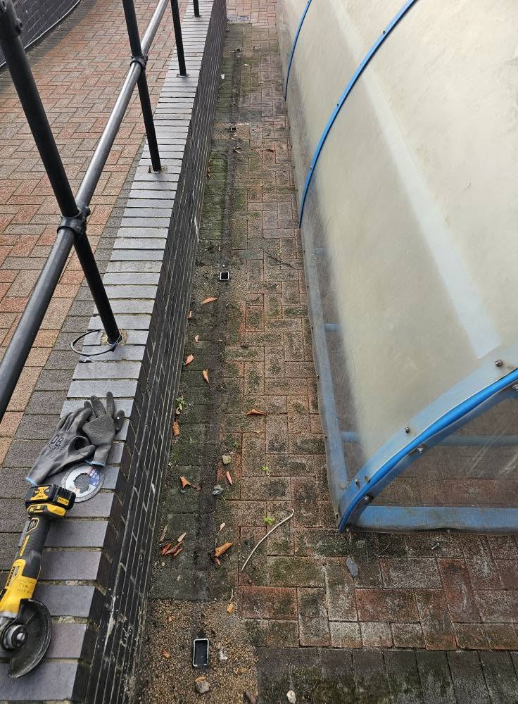Looking down at the re-clad cycle shelter roof at Stewart Fleming Primary School, London, tools on the paving alongside