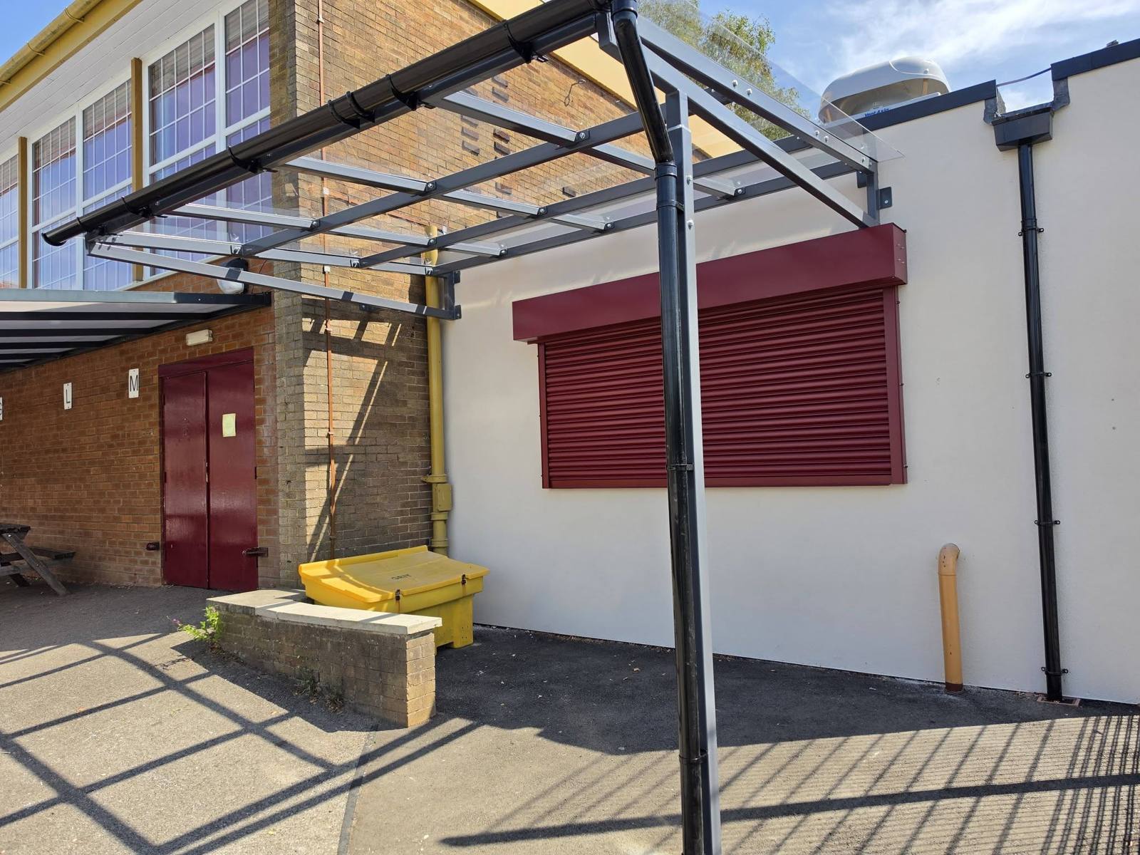 Underside of the canopy frame showing the glazed roof and roller shutter servery at Stockport School
