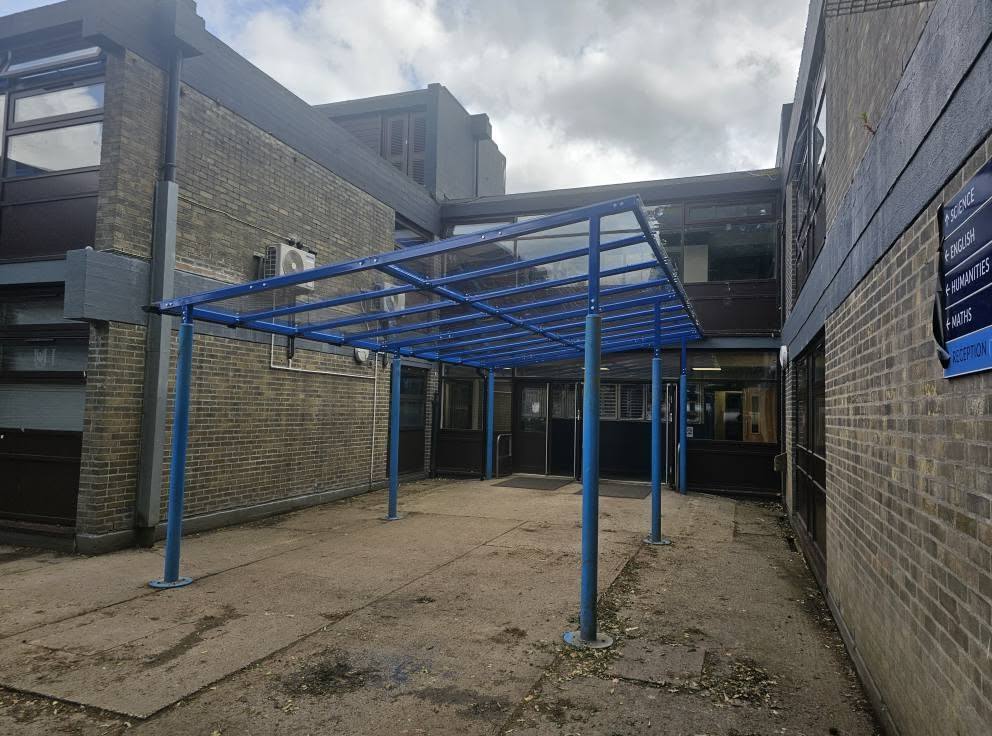 Side-on view of the blue canopy frame beside a wayfinding sign for departments and reception