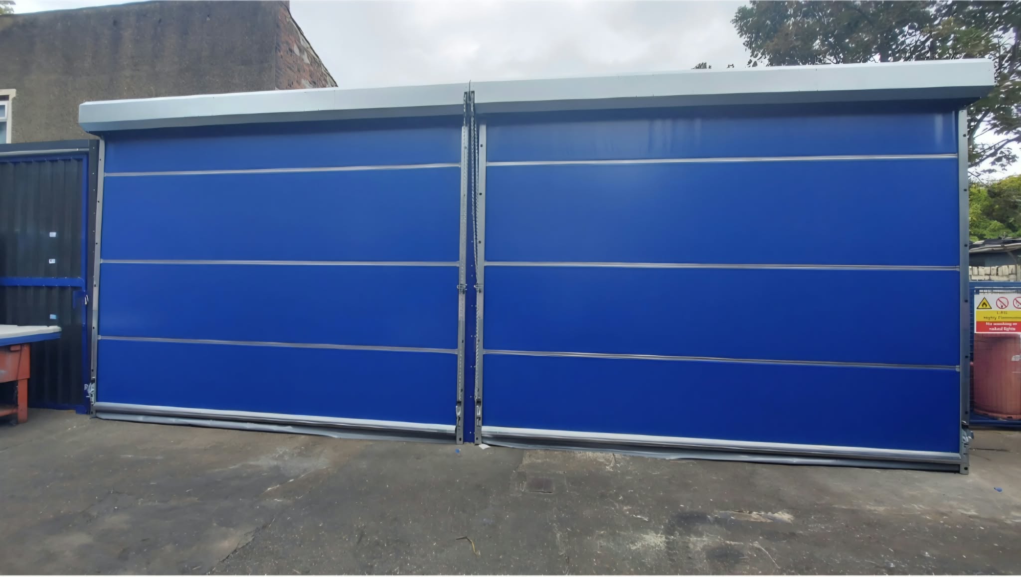 Two bright blue sliding door panels closed across the front of the steel storage shelter