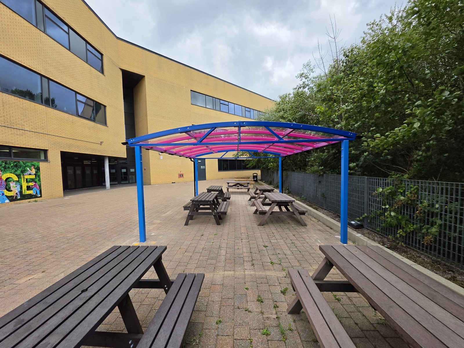 Establishing shot of the curved dining shelter beside the college building and courtyard